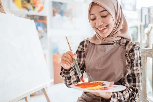 Artiste féminine asiatique musulmane peignant sur toile