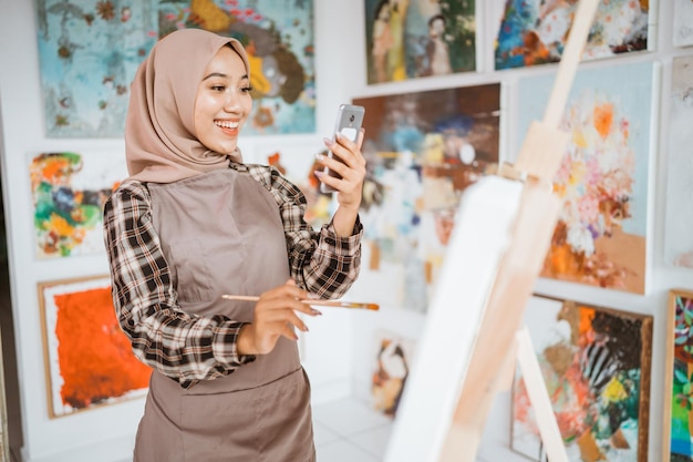 Artiste féminine musulmane à la recherche de l'inspiration de son téléphone portable