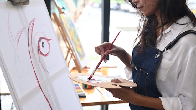 Artiste féminine peignant sur toile dans un studio moderne.