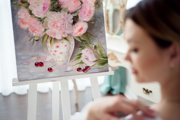 Artiste féminine peint une image sur toile avec des peintures à l'huile à la maison, vue arrière.