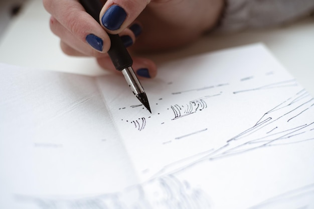 Photo artiste féminine regarde son travail dessin avec un stylo et de l'encre noire peinture graphique création d'art moderne