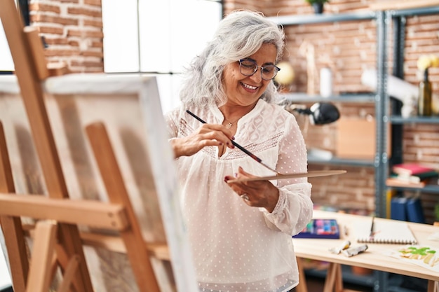 Artiste femme d'âge moyen souriant dessin confiant au studio d'art