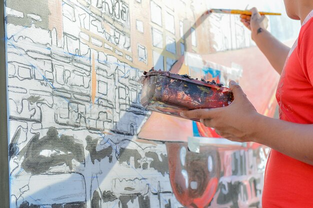 Artiste homme peinture sur le mur et tenant le bac à peinture à la main