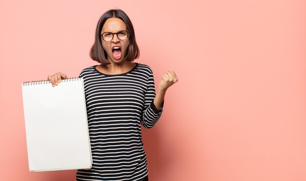 Artiste de la jeune femme criant de manière agressive avec une expression de colère ou avec les poings serrés célébrant le succès