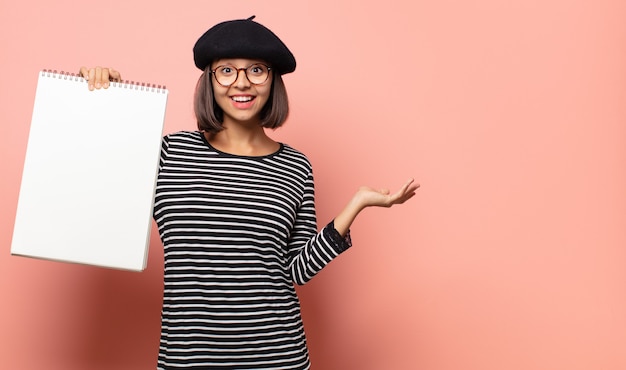 Photo artiste jeune femme se sentir heureux, surpris et joyeux, souriant avec une attitude positive, réalisant une solution ou une idée