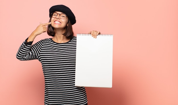 Artiste de la jeune femme souriant avec confiance en montrant son large sourire, attitude positive, détendue et satisfaite