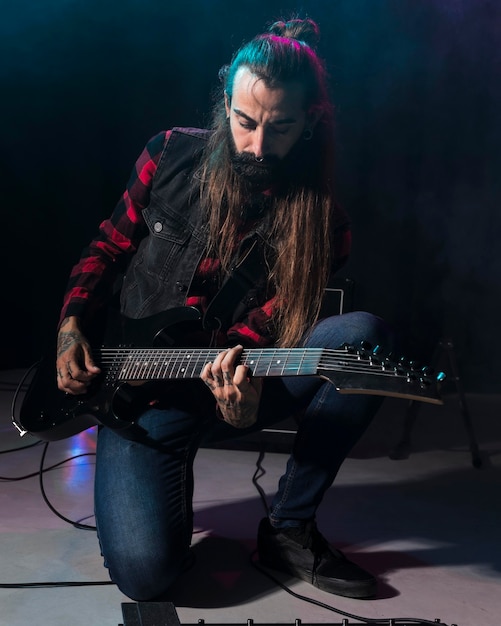 Photo artiste jouant de la guitare et assis dans son genou