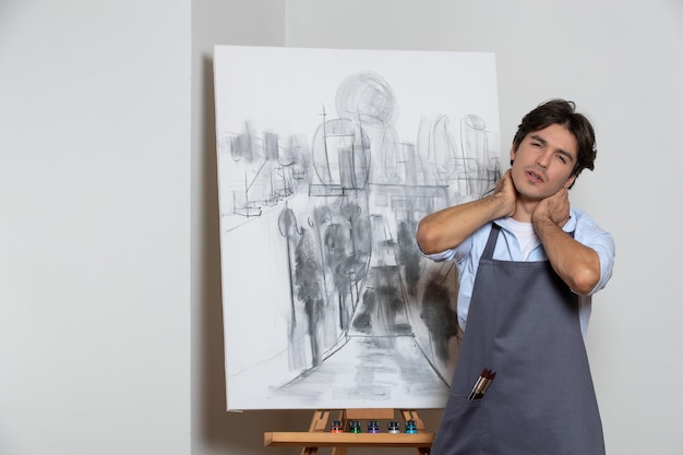 Artiste masculin fatigué posant avec son studio de peinture dessin de fond blanc