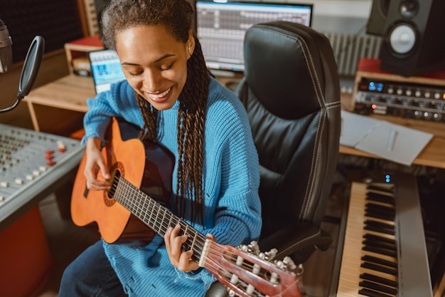 Artiste musicien afro-américain créatif travaillant sur la création d'une nouvelle chanson jouant de la guitare dans un studio d'enregistrement