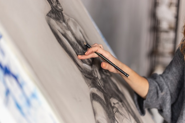 Photo artiste peignant sur chevalet en studio. femme peintre vue de côté.