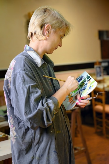 Artiste peintre femme peintre concentrée et inspirée, tableau avec pinceau et couleurs à l'huile sur toile