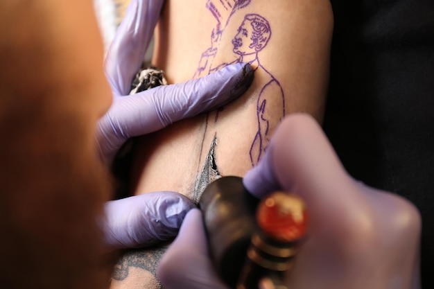 Artiste professionnel faisant le tatouage dans le salon vue rapprochée