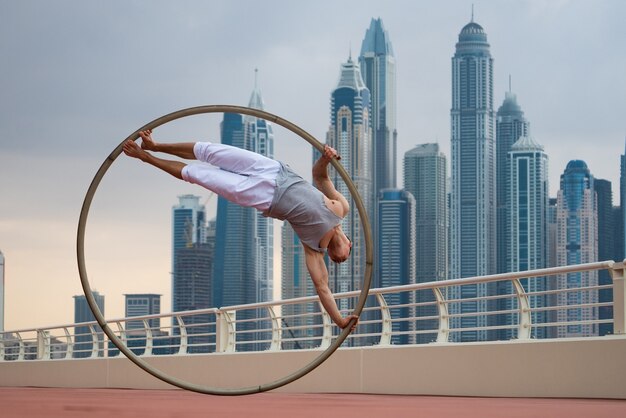 Artiste de la roue Cyr avec surface de paysage urbain de Dubaï pendant le coucher du soleil