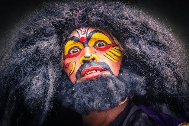 Un artiste se maquille le visage avant une représentation sur scène lors d'un festival indien
