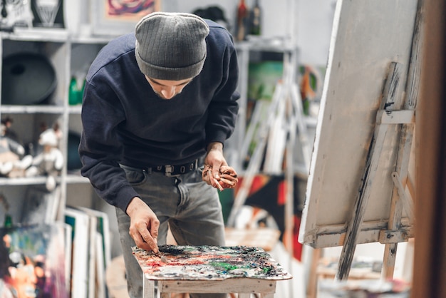 artiste tenant un pinceau à la main et ramasser la peinture avec un couteau à palette