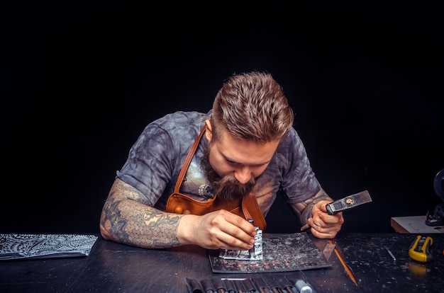 Artiste travaillant le cuir créant un nouveau produit en cuir dans l'atelier de tannerie.