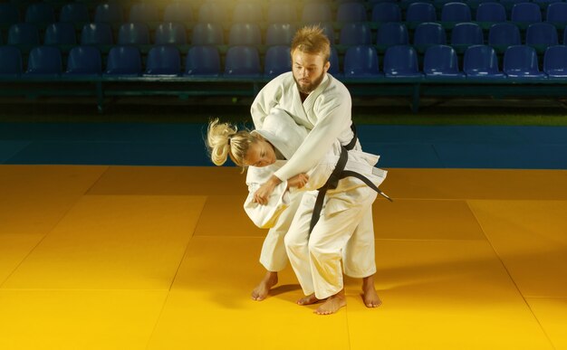 Arts martiaux. épargner les porteurs. Sport homme et femme en kimono blanc train judo jette et capture dans la salle de sport