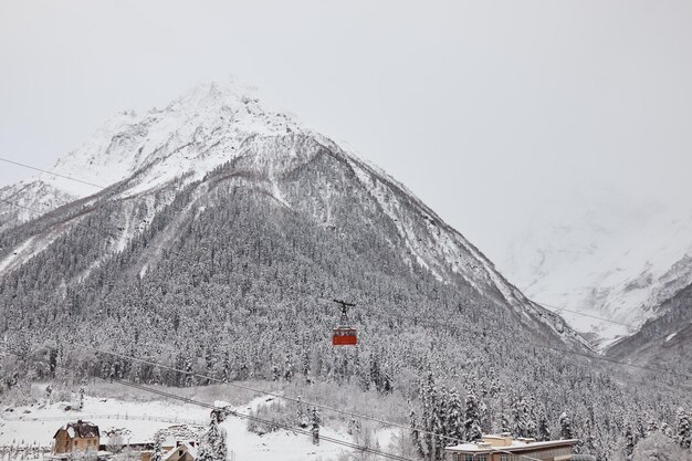 Ascenseur à pendule dans les montagnes téléphérique cabine rouge neige d'hiver sur les pentes et elle sur la forêt