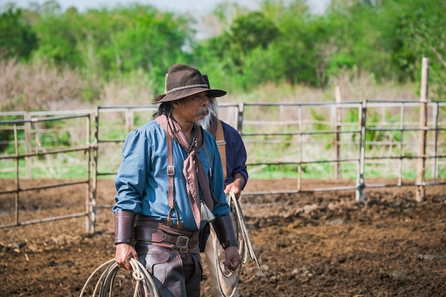 Asian Man Cowboy attrape un veau Pour être marqué dans un ranch