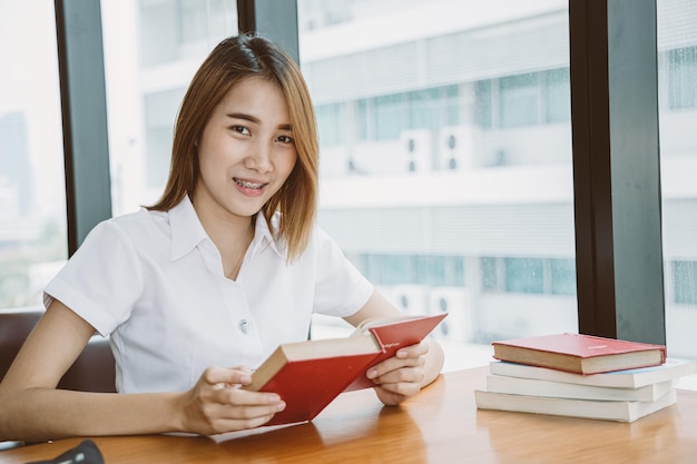 Asian University Teen Girl Sourire Heureux D'apprendre Et De L'éducation En Lisant Un Livre à La Bibliothèque