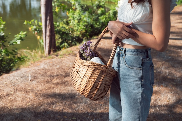 Asian woman holding panier en rotin avec fleur et tissu pour pique-nique sous le soleil