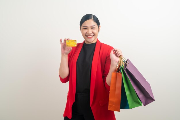 Asian woman holding shopping bag et carte de crédit en main avec fond blanc