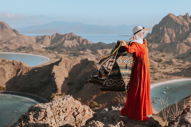 Asian woman in summer hat and dress standing on top hill et holding kain songket à Padar Island L