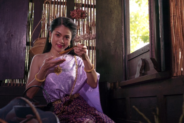 Asian woman wearing Thai costume traditionnel selon la culture et la tradition de la cuisine dans la cuisine à l'ancienne maison Ayutthaya, Thaïlande