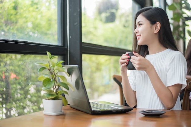 Asiat au café travaillant avec un ordinateur portable et une tasse de café