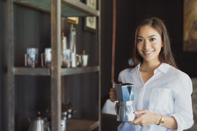 Asiat debout tenant un pot de café Sourire et s&#39;amuser Se détendre dans un café après avoir travaillé