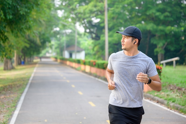 Asiatique beau jeune homme faisant de l'exercice en courant dans le parc transpiration des séances d'entraînement du matin