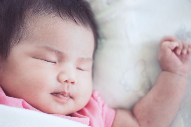 Asiatique bébé nouveau-né dort sur le lit blanc