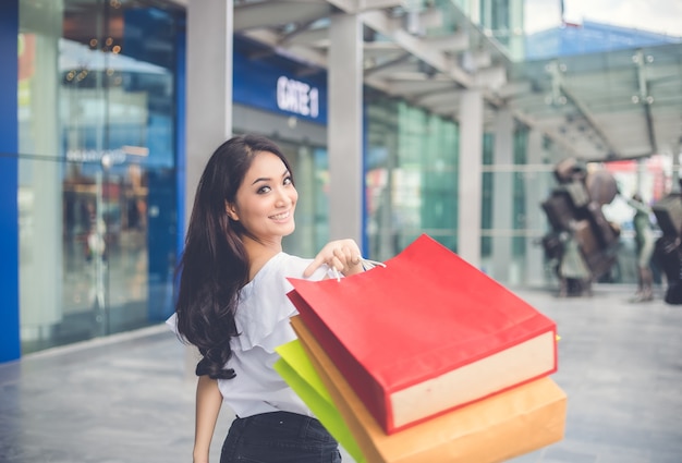 Asiatique Belle fille tient des sacs à provisions en souriant tout en faisant du shopping