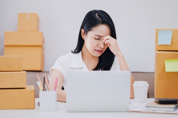 Asiatique belle jeune femme d'affaires se sentant maux de tête et stress dans les bureaux avec boîte de produit.