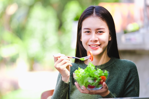 Asiatique belle jeune fille mangeant des légumes de salade