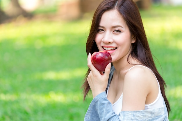 Asiatique belle jeune fille à la pomme rouge sur un fond de nature verdoyante