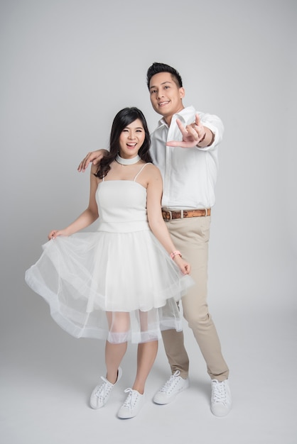 Asiatique couple amoureux en robe de mariée occasionnelle montrant je t'aime geste