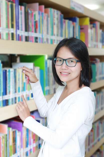 Asiatique dans la bibliothèque, sélection du livre à lire