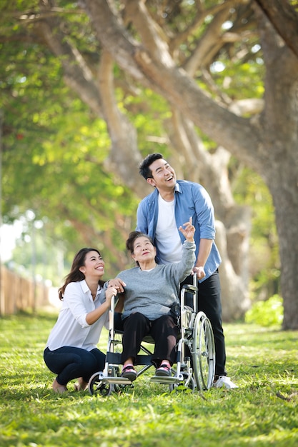 Asiatique femme âgée assise sur le fauteuil roulant avec la famille sourire heureux visage sur le parc verdoyant