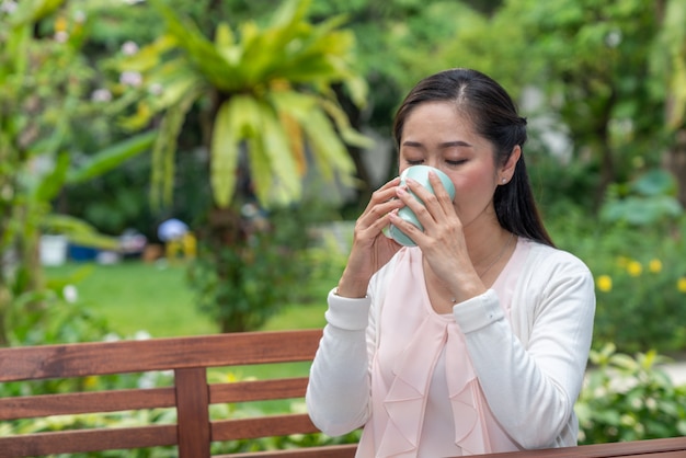 Asiatique femme assise avec une tasse de café à la maison jardin