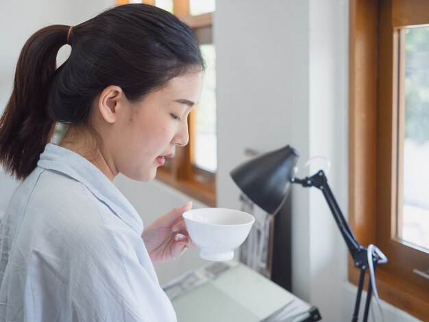 Asiatique femme buvant du café dans la salle de travail