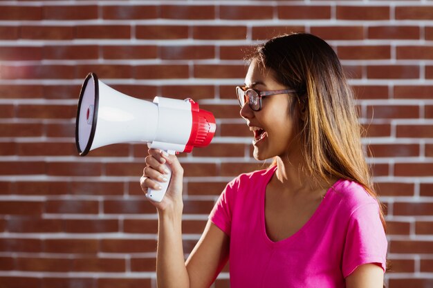 Asiatique femme criant au mégaphone sur le mur de briques