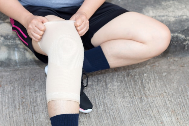 Photo asiatique femme ou femme sportive portant le support de genou ou la sangle du genou de l'athlète
