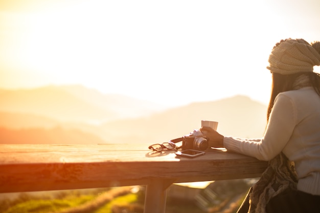 Asiatique femme heureuse et se détendre boire du café au soleil assis à l&#39;extérieur sous le soleil