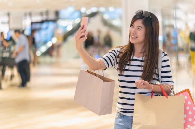 Asiatique femme marchant et utilisant le téléphone mobile intelligent pour selfie avec maquette de maquette