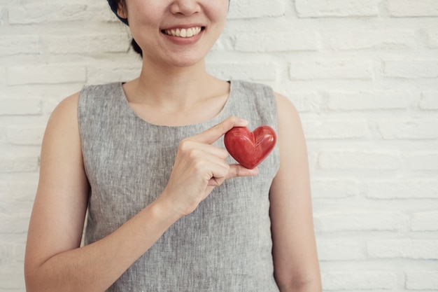 Asiatique femme tenant coeur rouge, assurance maladie, concept de charité de don