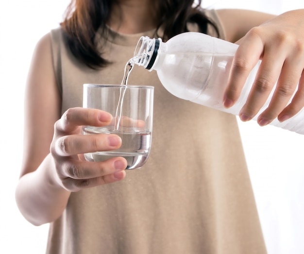 Asiatique femme versant de l&#39;eau à partir d&#39;une bouteille en plastique dans un verre