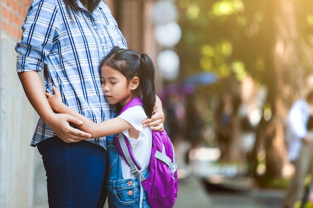 Asiatique fille élève avec sac à dos étreignant sa mère avec tristesse avant d&#39;aller en classe à l&#39;école.