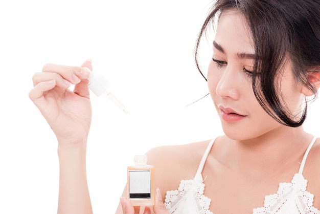 Asiatique jeune belle femme souriante shes tenant une bouteille de sérum pour les cheveux ou les soins de la peau