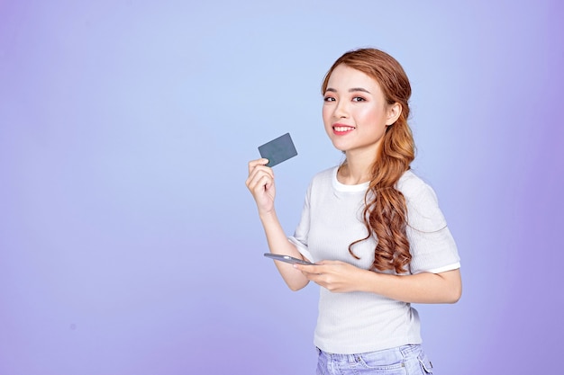 Asiatique jeune belle jolie jolie étudiante tenant une carte de crédit et un téléphone intelligent